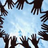 Circle of hands held out in unity against blue sky
