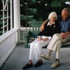 An elderly couple sits on a porch swing.